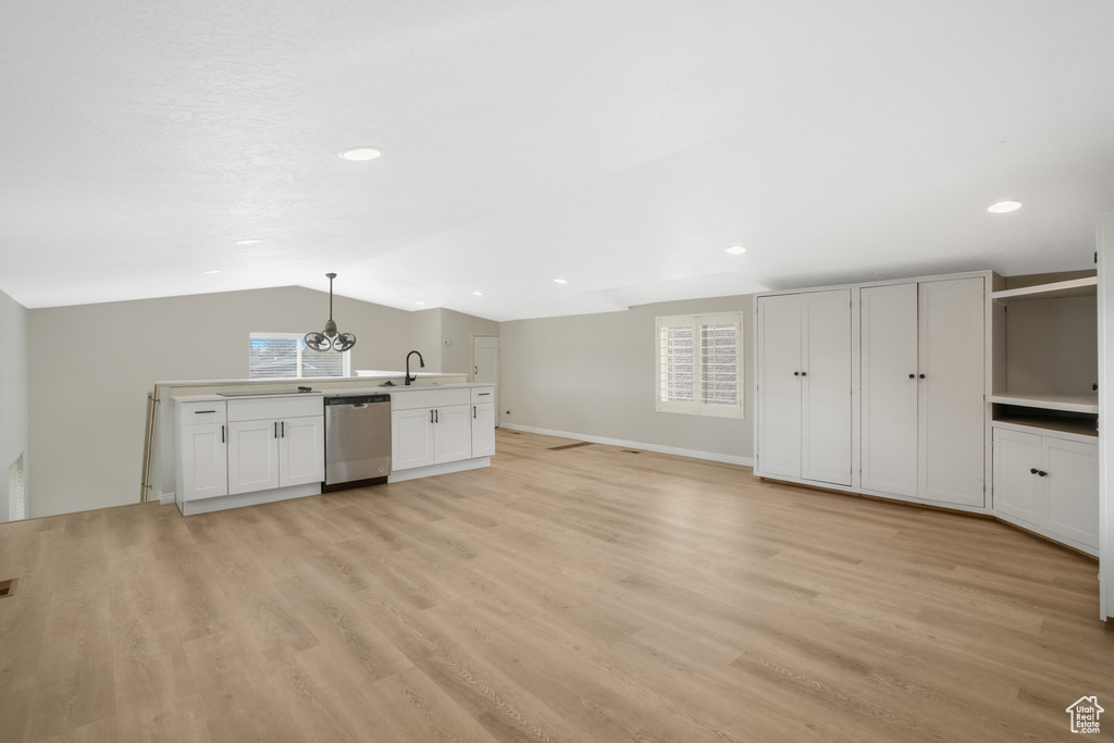 Unfurnished living room featuring a wealth of natural light, vaulted ceiling, and light wood-type flooring