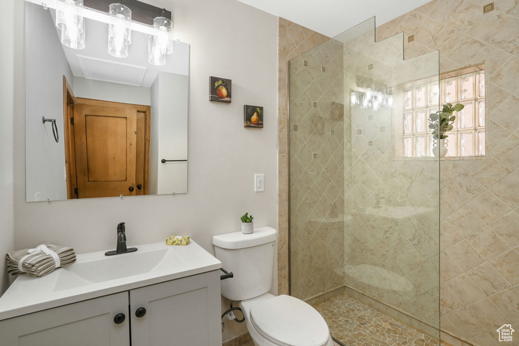 Bathroom with tiled shower, vanity, and toilet