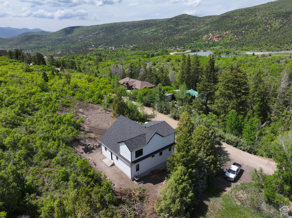 View of subject property featuring a mountainous background and a heavily wooded area