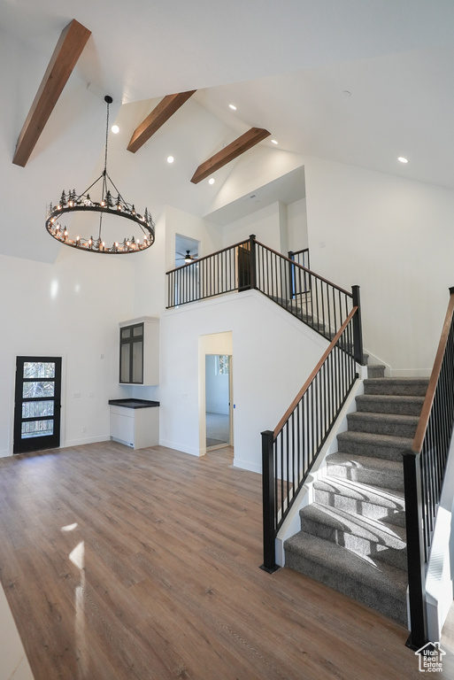 Unfurnished living room featuring beamed ceiling, wood-type flooring, and high vaulted ceiling