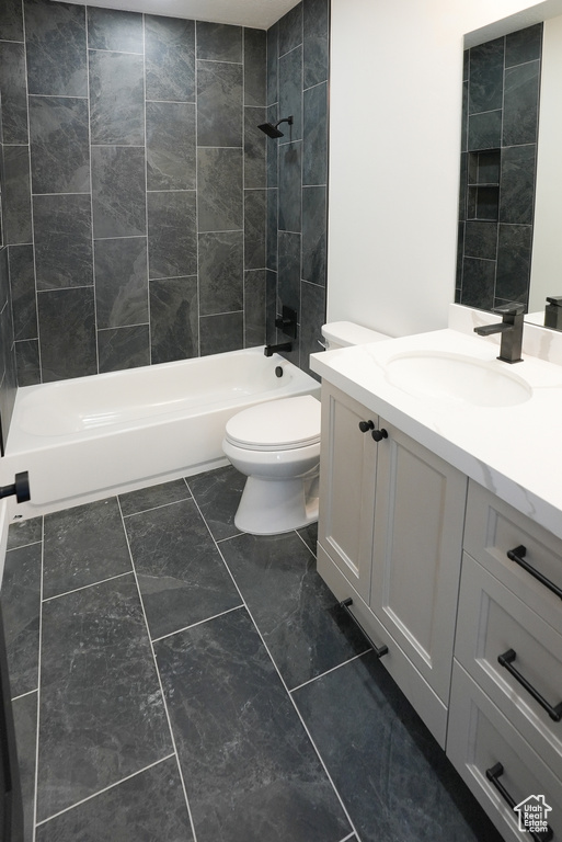 Full bathroom with tiled shower / bath combo, vanity, and toilet