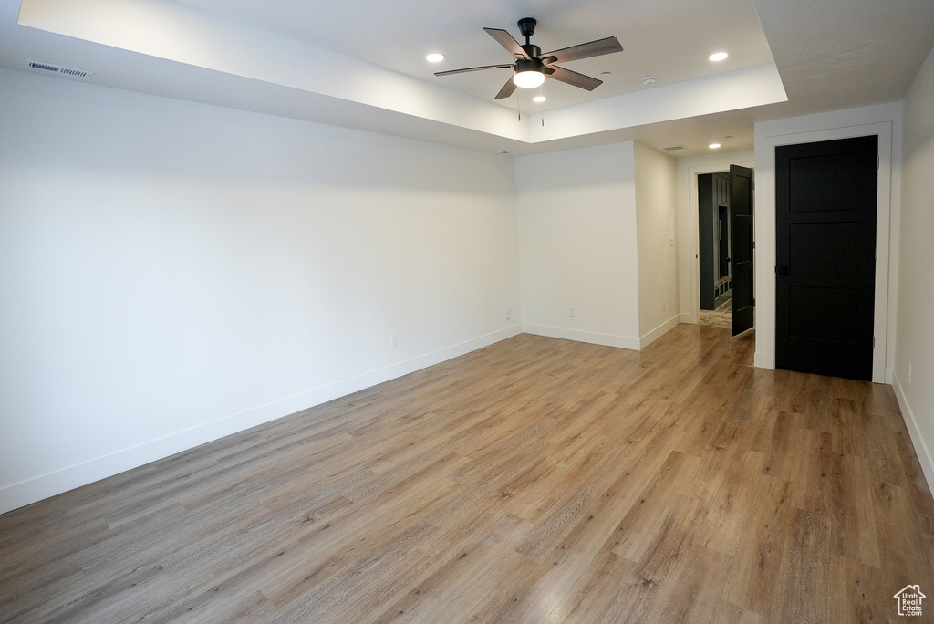 Spare room with light hardwood / wood-style flooring, a raised ceiling, and ceiling fan