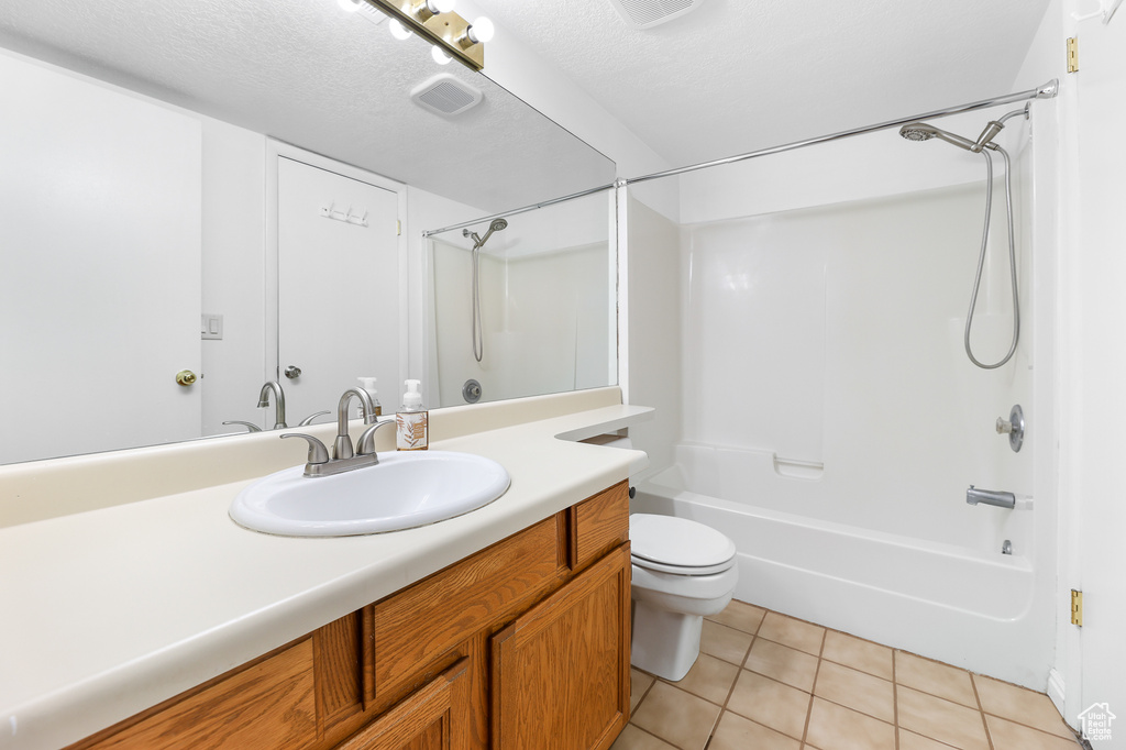 Full bathroom with vanity, a textured ceiling, tile patterned floors, shower / bathing tub combination, and toilet