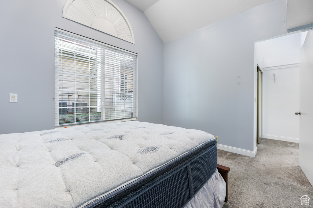 Bedroom with light carpet and vaulted ceiling