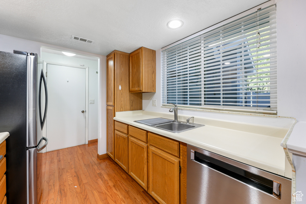 Kitchen featuring sink, stainless steel appliances, light hardwood / wood-style floors, and a textured ceiling