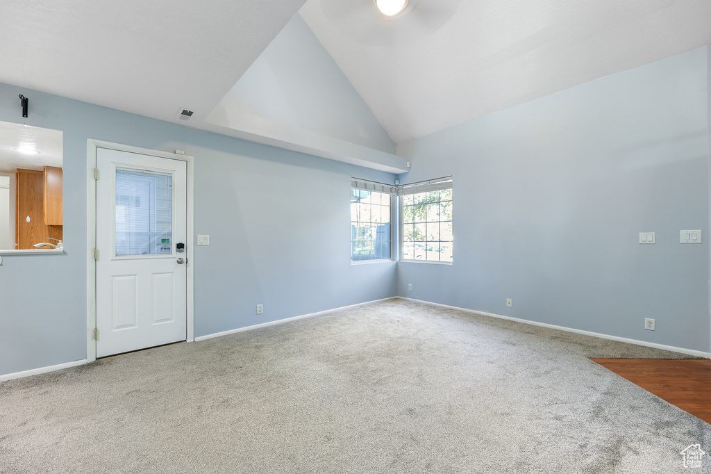 Carpeted spare room with vaulted ceiling