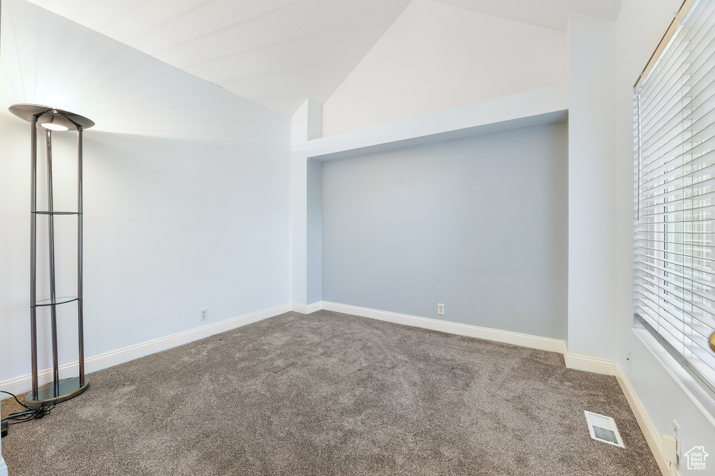 Carpeted spare room with high vaulted ceiling