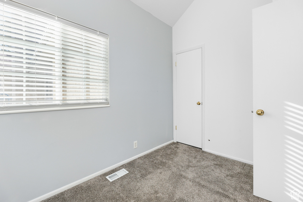 Unfurnished room featuring lofted ceiling and light colored carpet