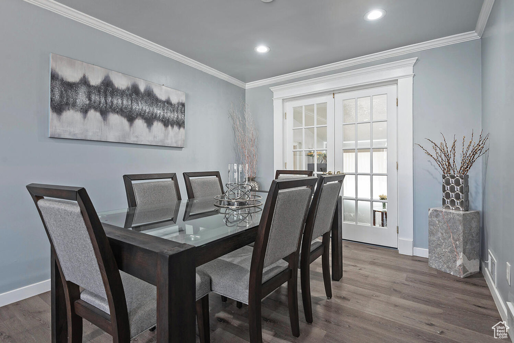 Dining space with ornamental molding and hardwood / wood-style floors