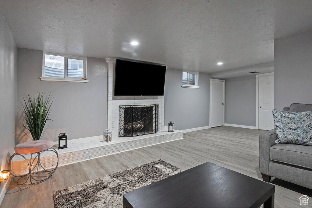 Living room with light hardwood / wood-style flooring, a brick fireplace, and a textured ceiling