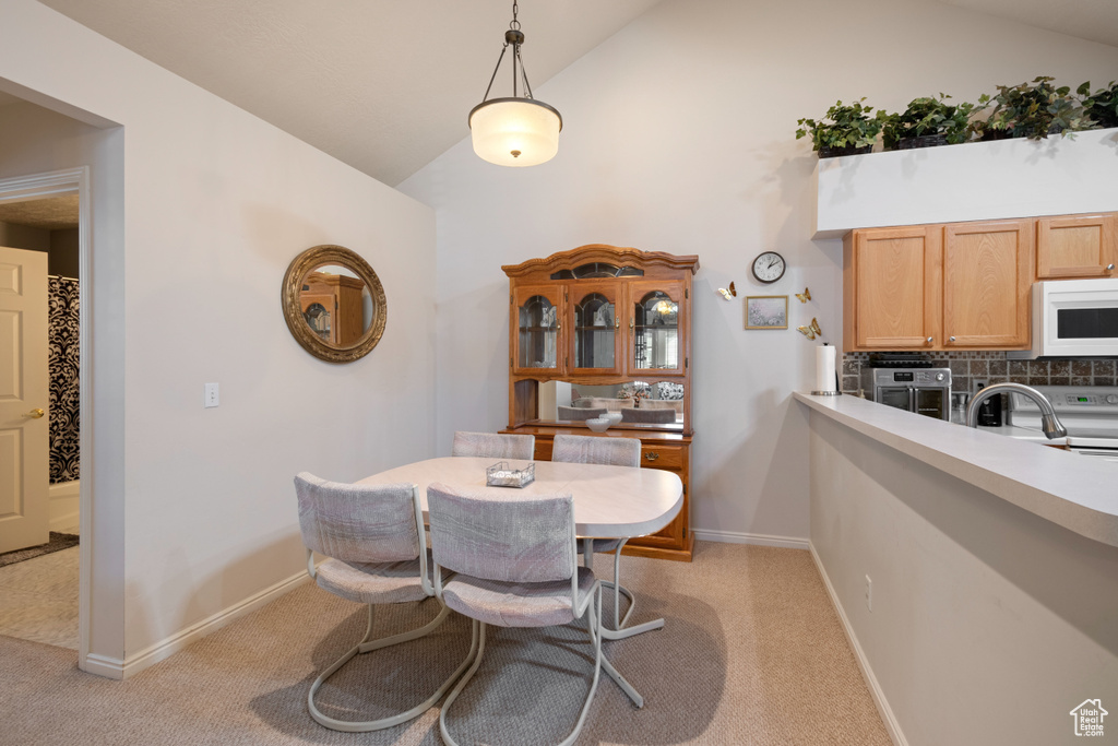 Dining area with lofted ceiling, sink, and light colored carpet