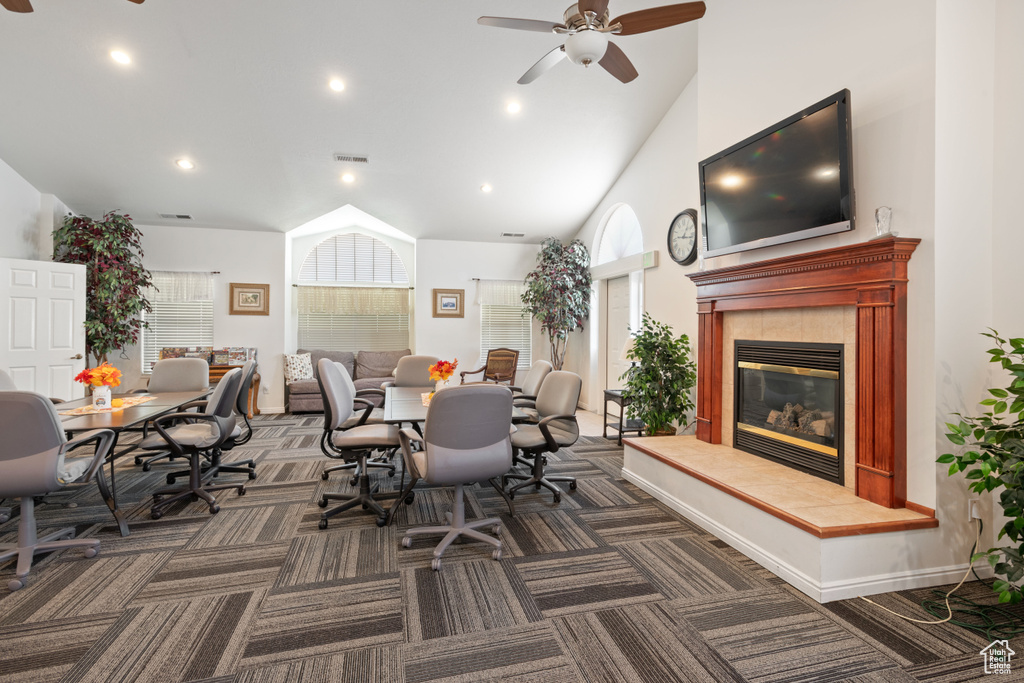 Dining room featuring a fireplace, vaulted ceiling, dark colored carpet, and ceiling fan