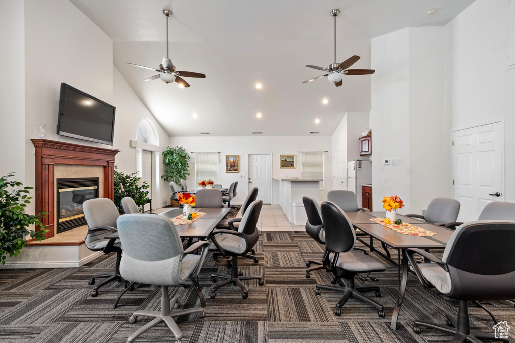 Carpeted dining room with high vaulted ceiling, a tiled fireplace, and ceiling fan