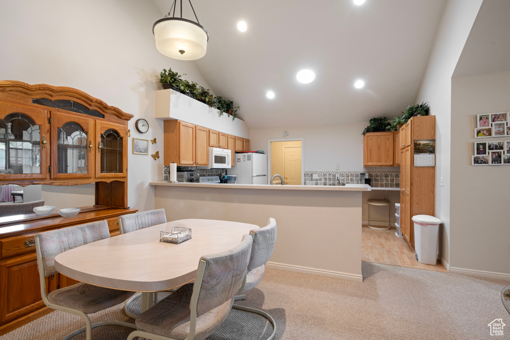 Carpeted dining area featuring high vaulted ceiling