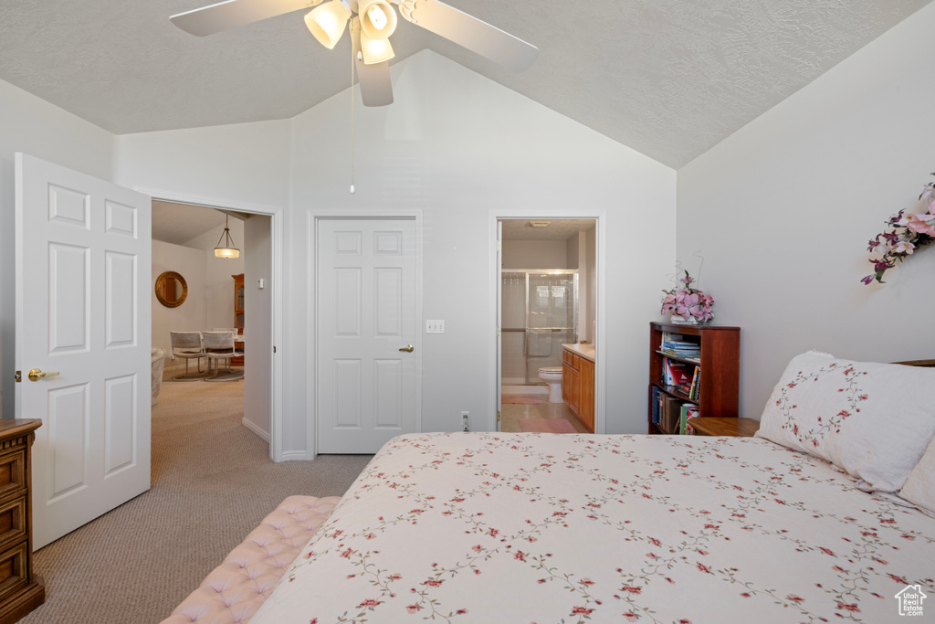 Bedroom featuring a textured ceiling, lofted ceiling, ceiling fan, ensuite bath, and light carpet