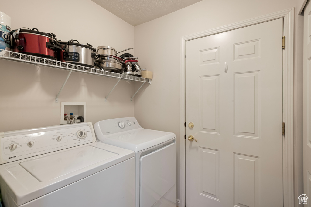 Laundry room with a textured ceiling and washing machine and dryer