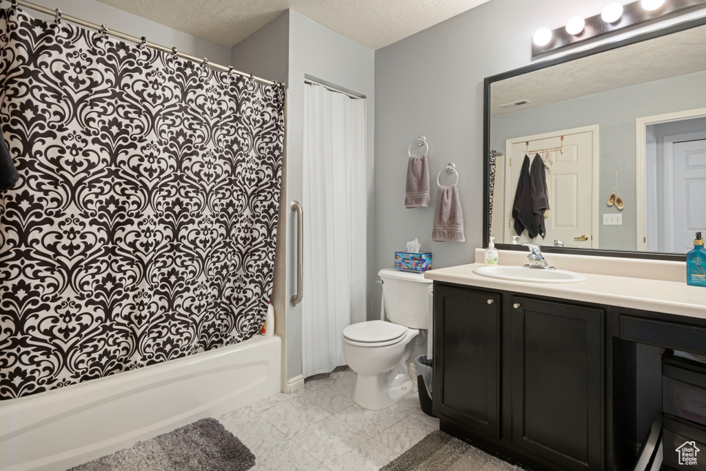 Full bathroom with a textured ceiling, shower / tub combo, vanity, and toilet