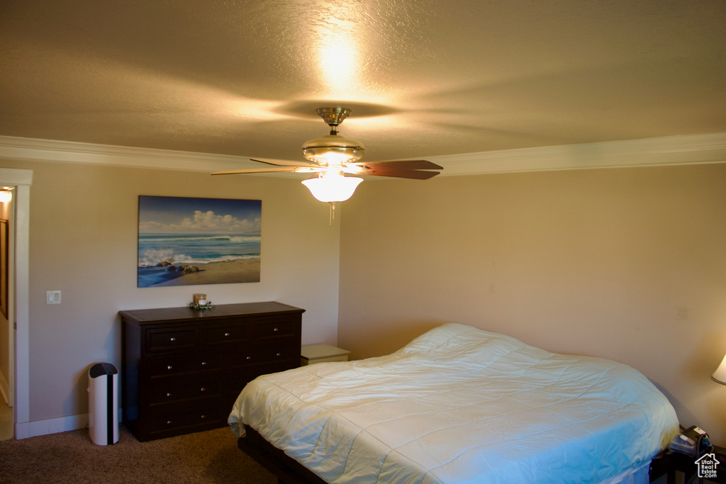 Carpeted bedroom featuring a textured ceiling, crown molding, and ceiling fan