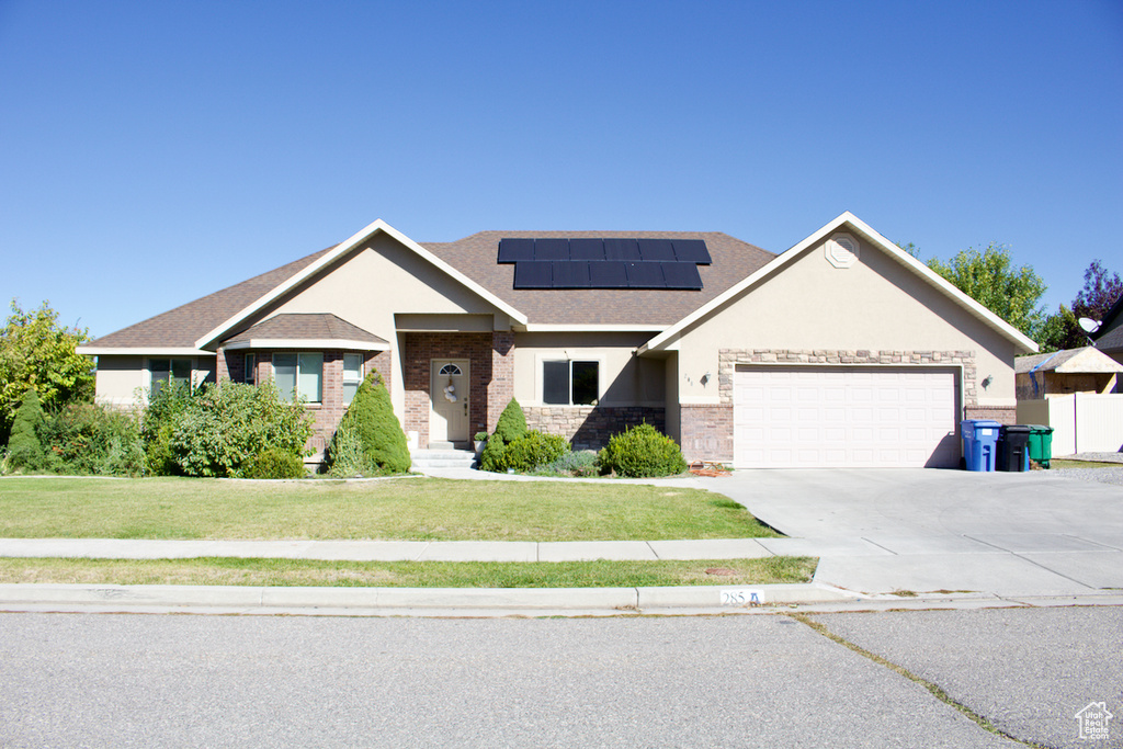 View of front facade with a garage, solar panels, and a front yard