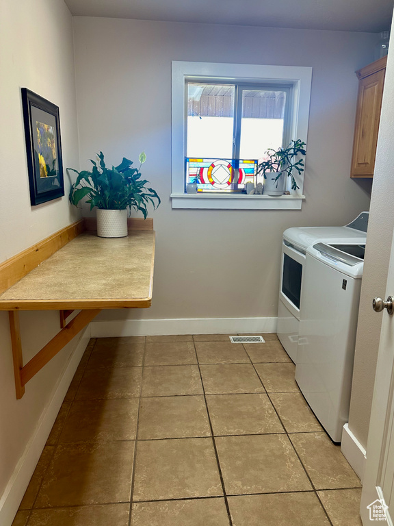 Laundry room with washer and clothes dryer, cabinets, and light tile patterned floors