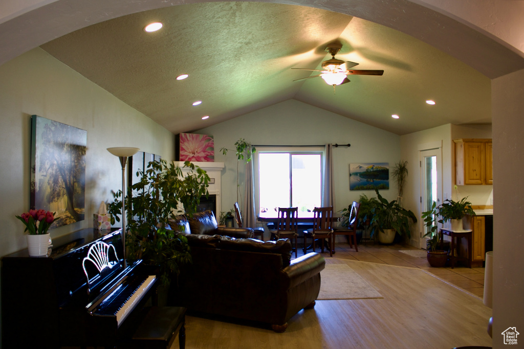 Living room featuring a textured ceiling, lofted ceiling, ceiling fan, and light hardwood / wood-style flooring