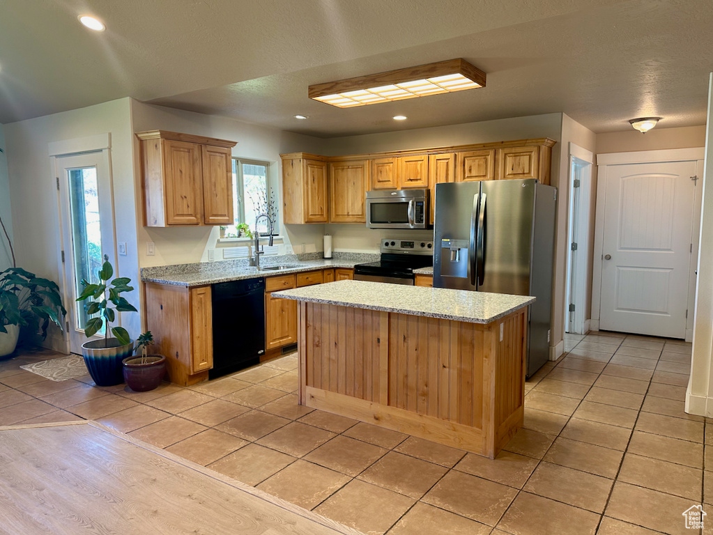 Kitchen with sink, a center island, stainless steel appliances, and light tile patterned floors