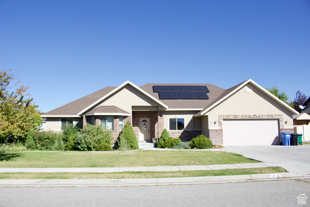 View of front of house with a front lawn, solar panels, and a garage