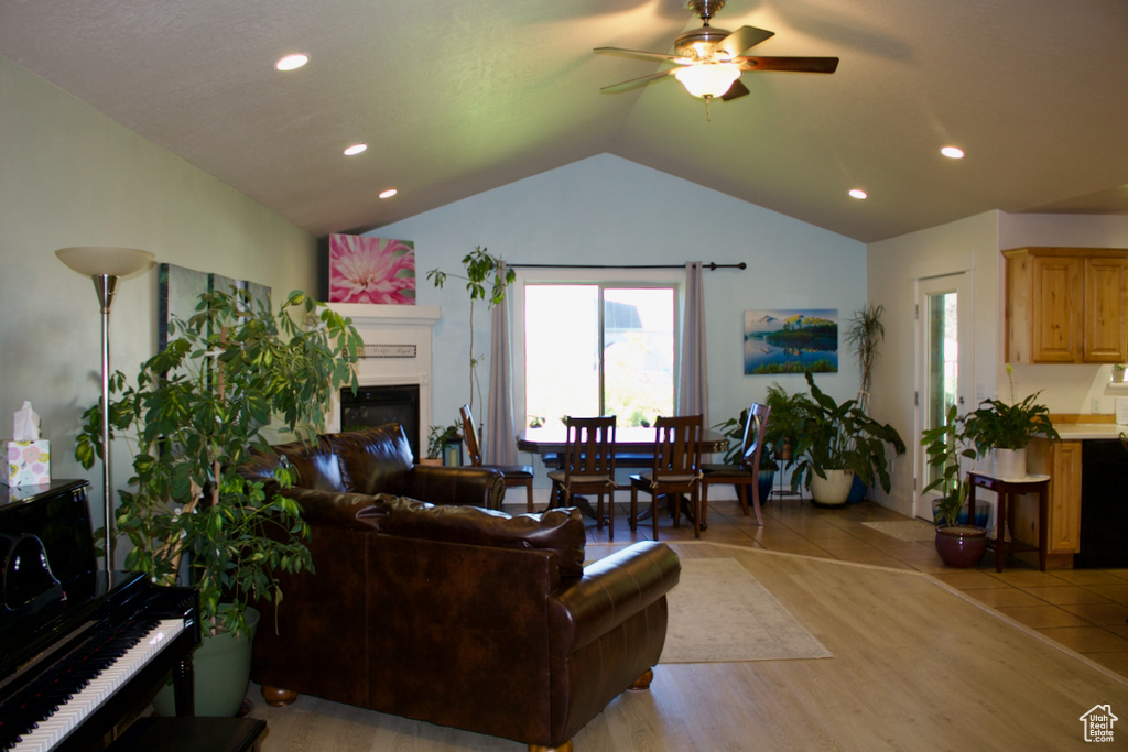 Living room with vaulted ceiling, ceiling fan, and light hardwood / wood-style flooring