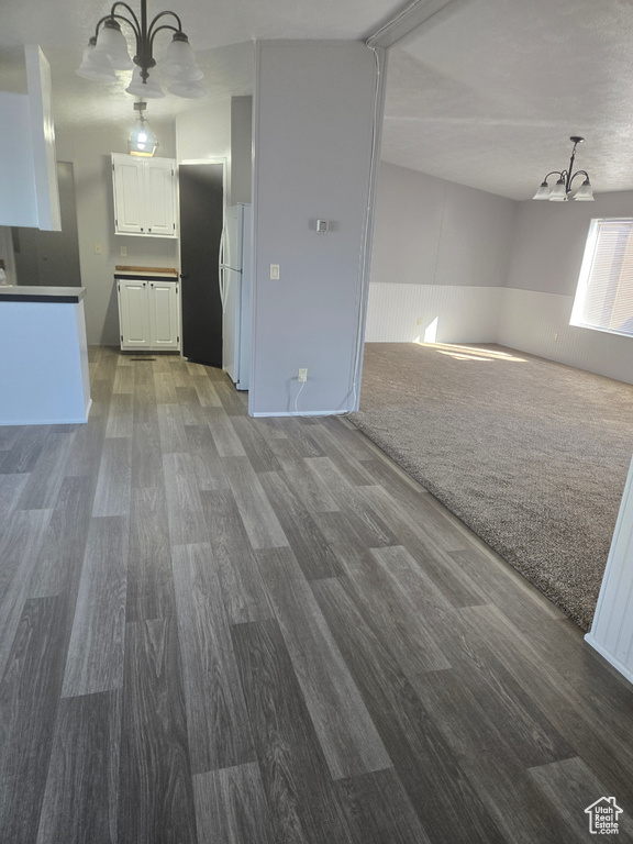 Unfurnished living room with wood-type flooring and a chandelier