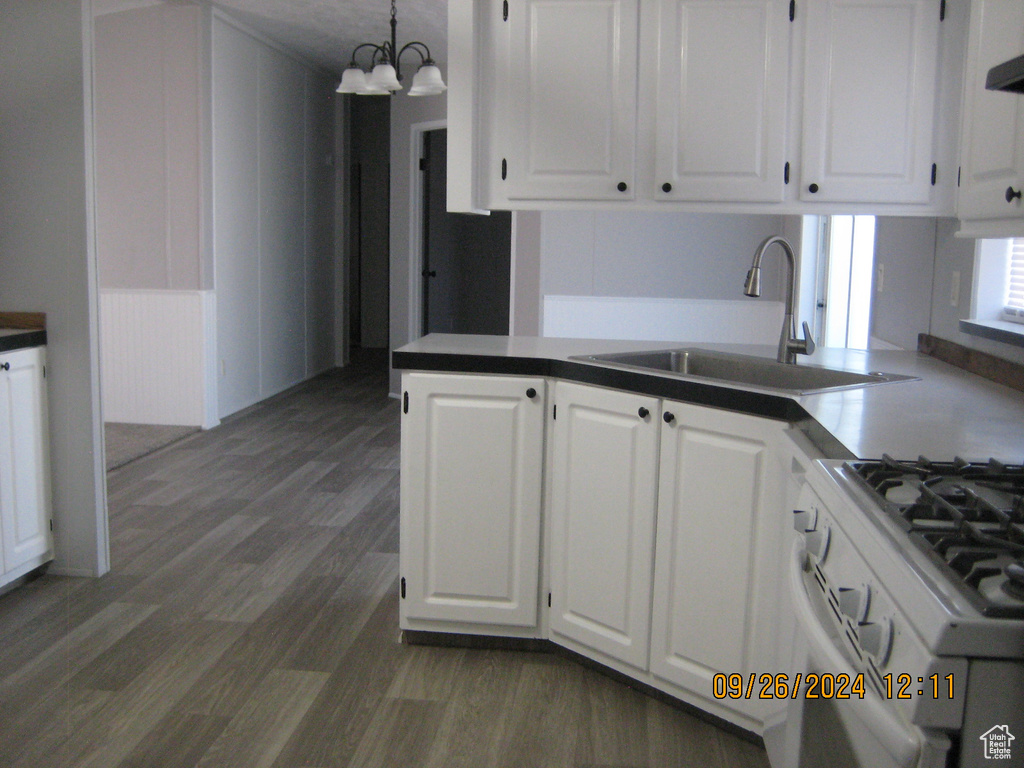 Kitchen with white cabinets, hanging light fixtures, sink, a chandelier, and dark hardwood / wood-style flooring