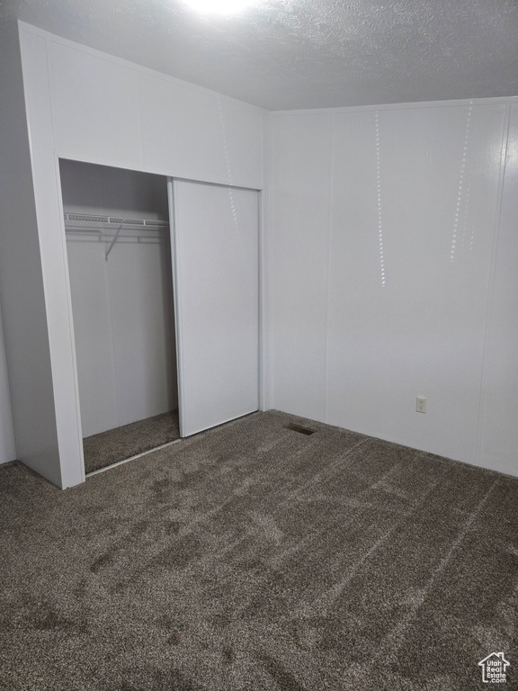 Unfurnished bedroom with carpet floors, a textured ceiling, and a closet