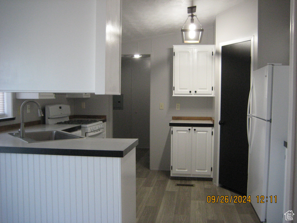 Kitchen featuring white cabinets, kitchen peninsula, sink, white appliances, and dark hardwood / wood-style flooring