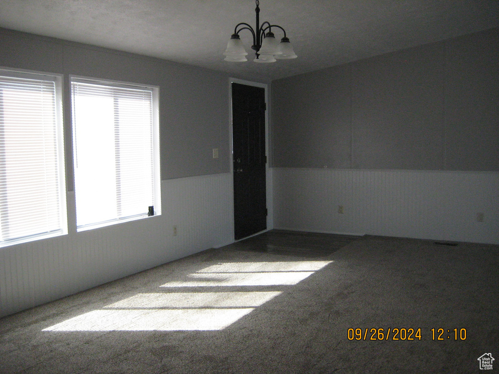 Spare room featuring an inviting chandelier, a textured ceiling, vaulted ceiling, and carpet