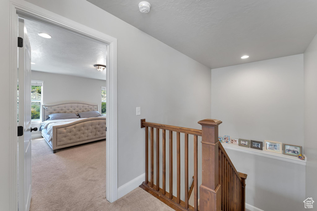 Hall with light colored carpet and a textured ceiling