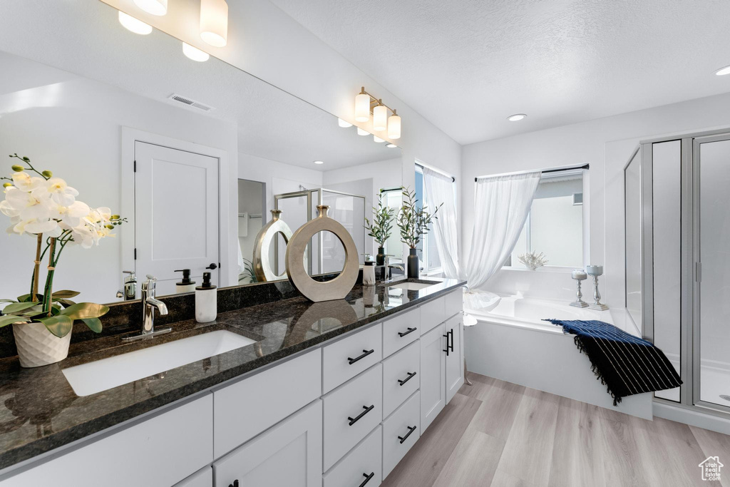 Bathroom with vanity, separate shower and tub, a textured ceiling, and wood-type flooring