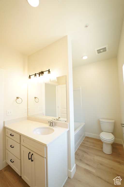 Full bathroom featuring shower with separate bathtub, vanity, toilet, and hardwood / wood-style flooring