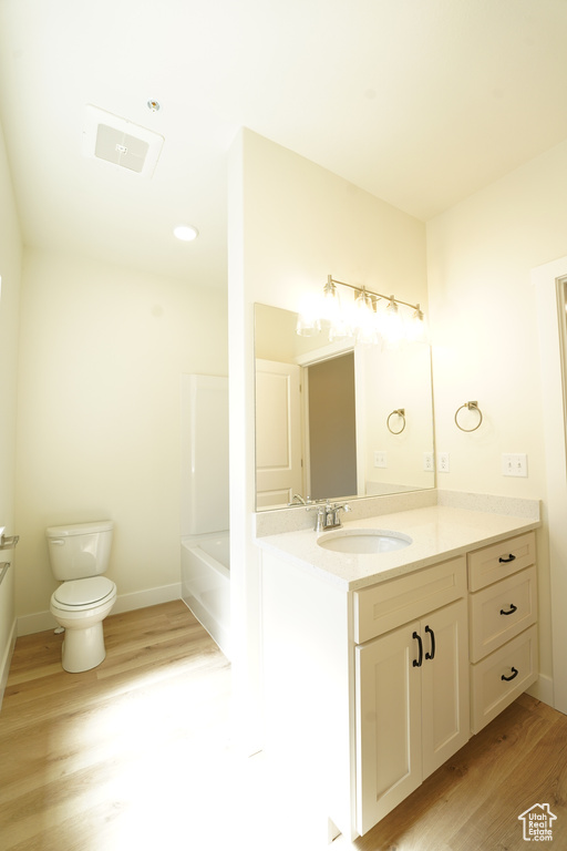 Bathroom featuring a bathtub, hardwood / wood-style floors, vanity, and toilet