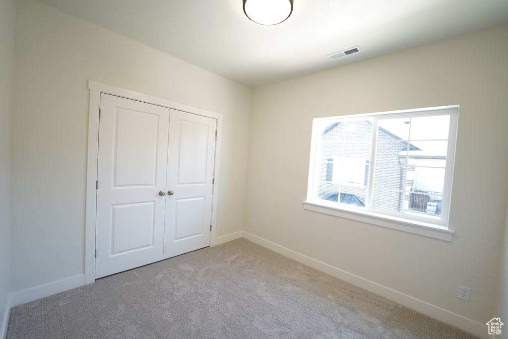 Unfurnished bedroom featuring light colored carpet and a closet