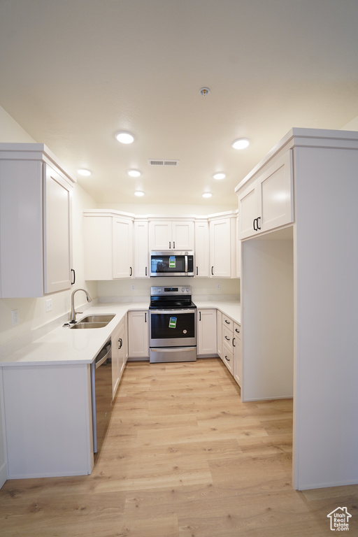 Kitchen featuring white cabinets, light hardwood / wood-style floors, appliances with stainless steel finishes, and sink