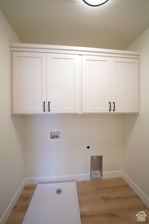 Washroom with hookup for a washing machine, cabinets, light hardwood / wood-style flooring, and hookup for an electric dryer