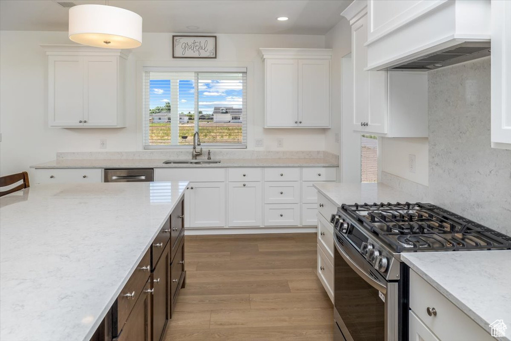 Kitchen with white cabinets, sink, stainless steel range with gas cooktop, and premium range hood