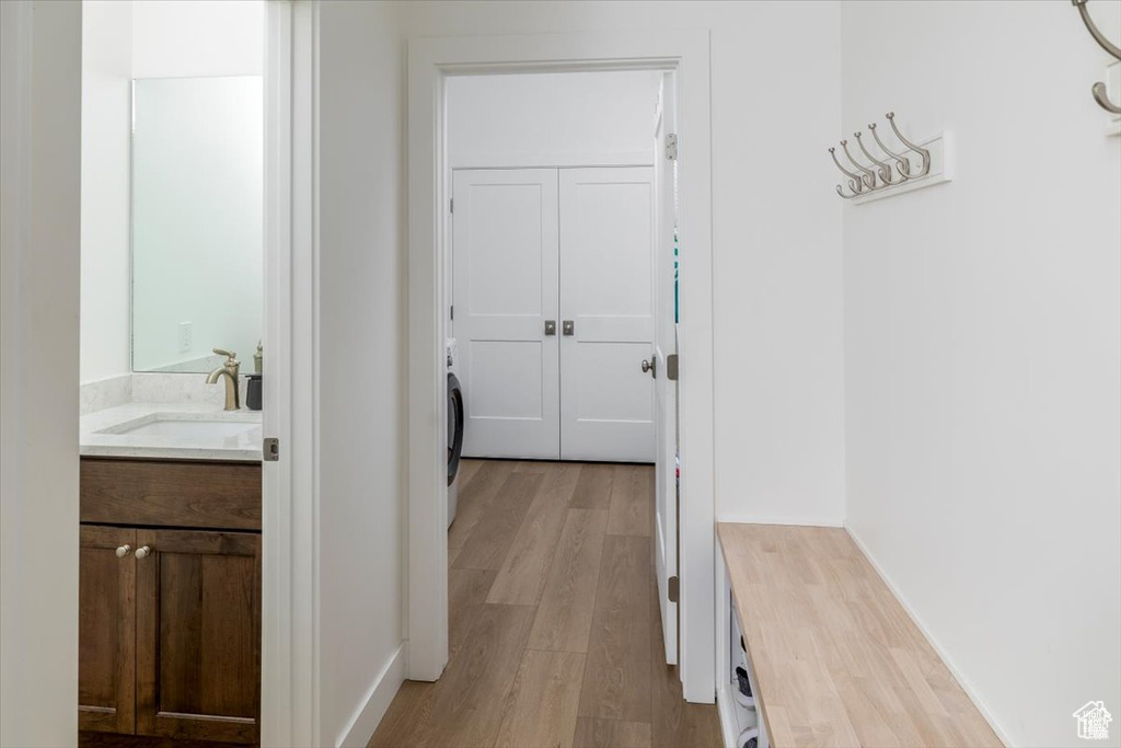 Corridor with light wood-type flooring, sink, and washer / dryer