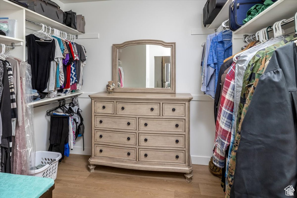 Walk in closet with light hardwood / wood-style flooring