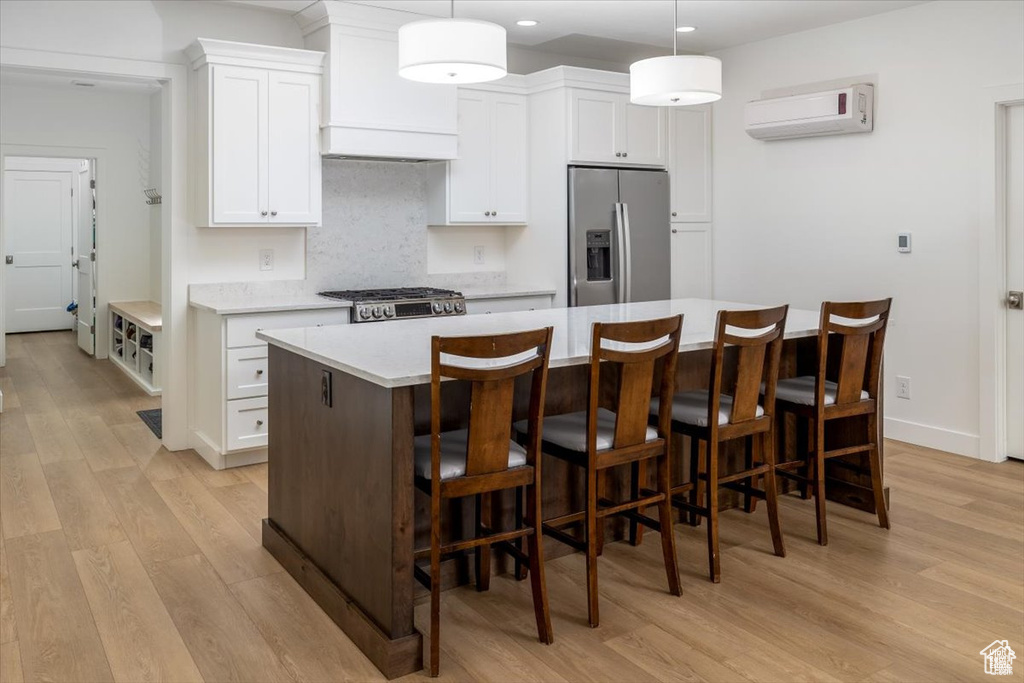 Kitchen featuring stainless steel appliances, light wood-type flooring, white cabinetry, and a kitchen island