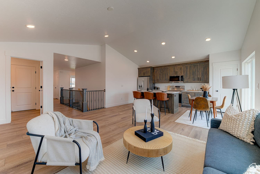 Living room with light hardwood / wood-style flooring and vaulted ceiling