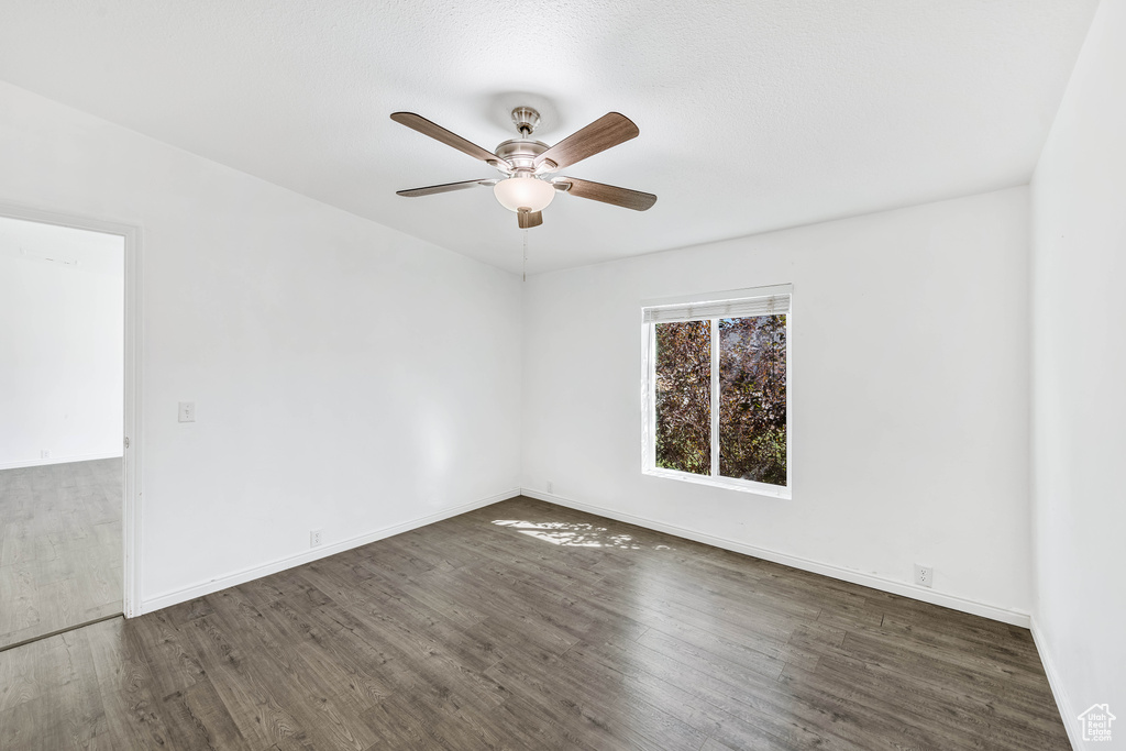 Empty room with dark wood-type flooring and ceiling fan