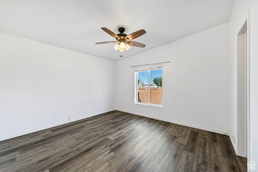 Empty room with ceiling fan, lofted ceiling, and dark hardwood / wood-style flooring