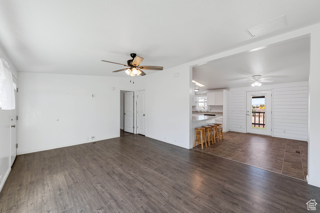 Unfurnished living room with ceiling fan and dark hardwood / wood-style flooring