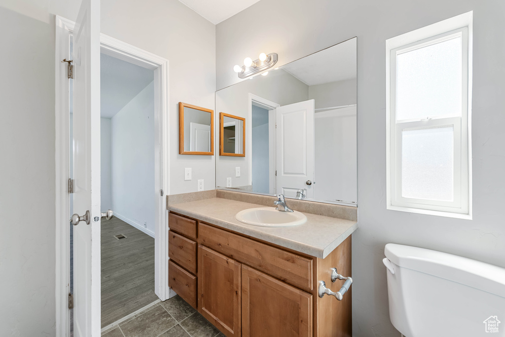 Bathroom with hardwood / wood-style floors, vanity, and toilet