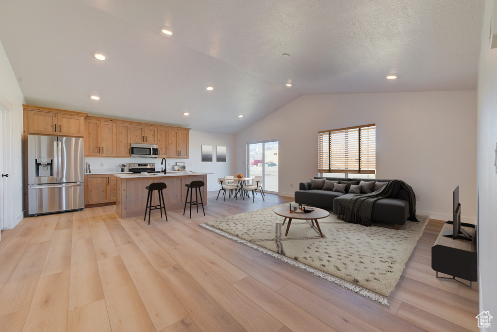 Living room with light hardwood / wood-style flooring, lofted ceiling, and sink